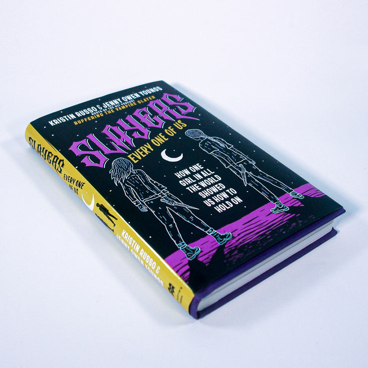 A hardcover memoir titled Slayers: Every One of Us by Buffering the Vampire Slayer features queer women, with cover art showing two figures apart under a crescent moon, bold purple title, and yellow, white, and pink accents on a dark background.