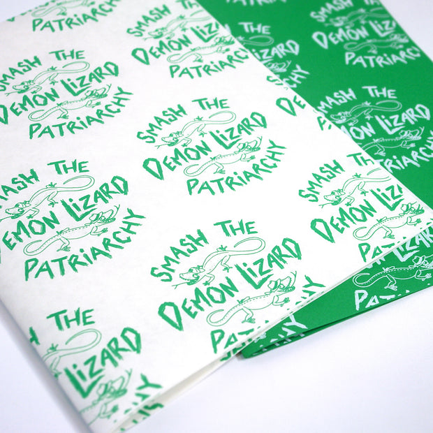 image of green and white and white and green wrapping paper. printed on the paper says smash the demon lizard patriarchy and a lizard