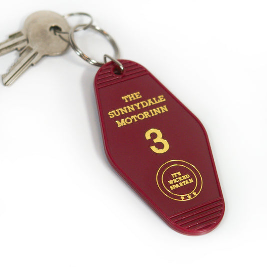 A set of silver keys on a maroon motel-style key tag from Buffering the Vampire Slayer labeled The Sunnydale Motor Inn 3 in yellow, featuring a circular design that says Its Wicked Spacious.