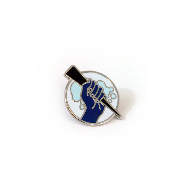 image of a circle enamel pin on a white background. pin is of a hand holding a stake.