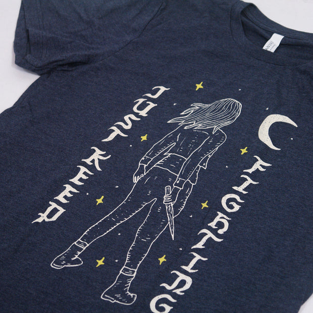 close up angled image of a navy tri blend tee shirt on a white background. tee has full chest print that says vertically on the left just keep with the back of a woman holding a stake in the middle and a cresent moon and fighting on the right