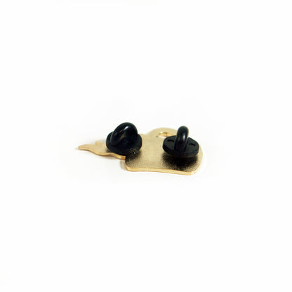 A gold enamel pin by Buffering the Vampire Slayer is shown from the back, displaying two black rubber clutch fasteners on a white background.